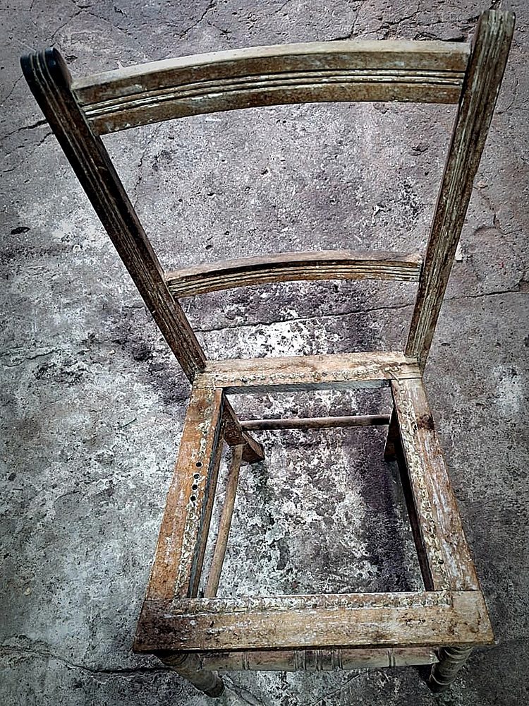 Silla antigua de madera antes de restaurar, con la superficie deteriorada